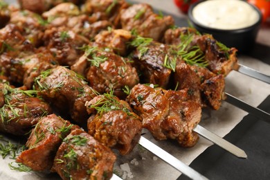 Metal skewers with delicious meat on table, closeup