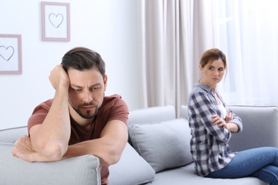Photo of Couple ignoring each other after argument in living room. Relationship problems