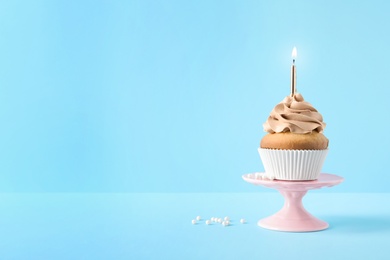 Dessert stand with delicious birthday cupcake on color background