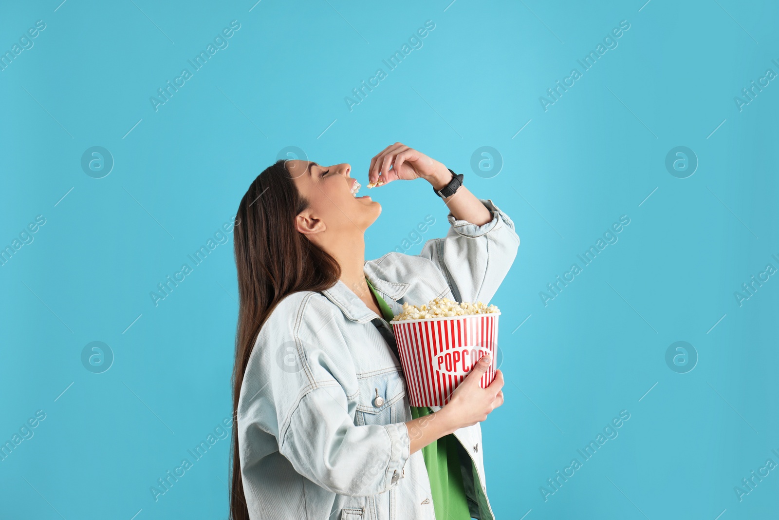 Photo of Young woman eating tasty popcorn on color background