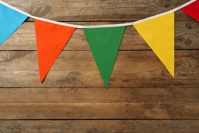 Bunting with colorful triangular flags on wooden background. Festive decor