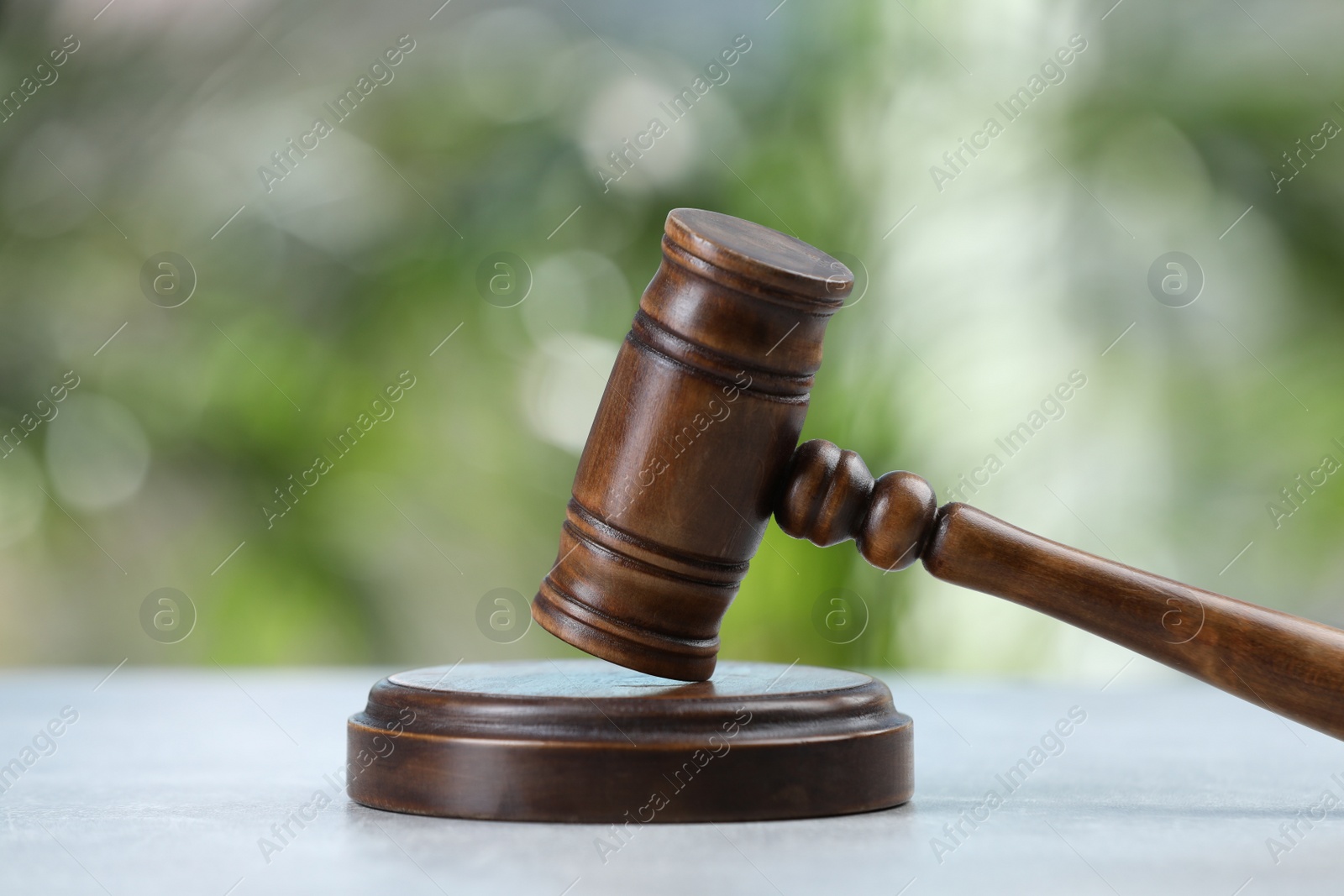 Photo of Wooden gavel on grey table against blurred background