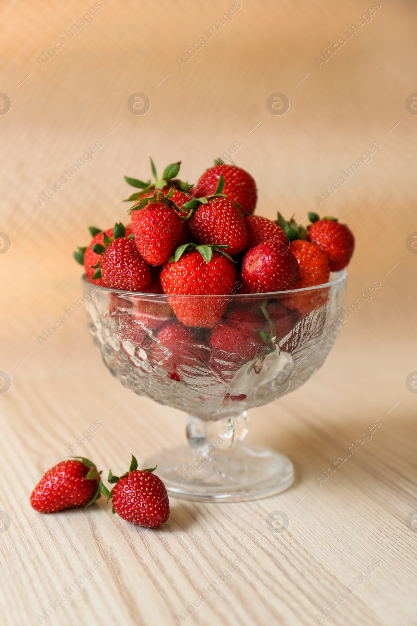 Photo of Glass dessert bowl with ripe strawberries on white wooden table