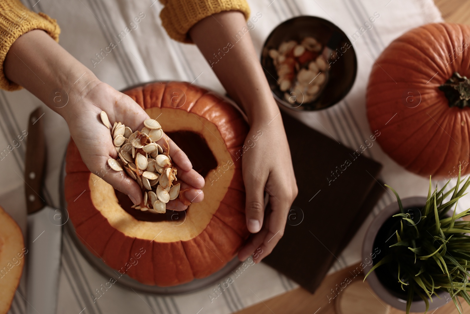 Photo of Woman making pumpkin jack o'lantern at table, top view. Halloween celebration