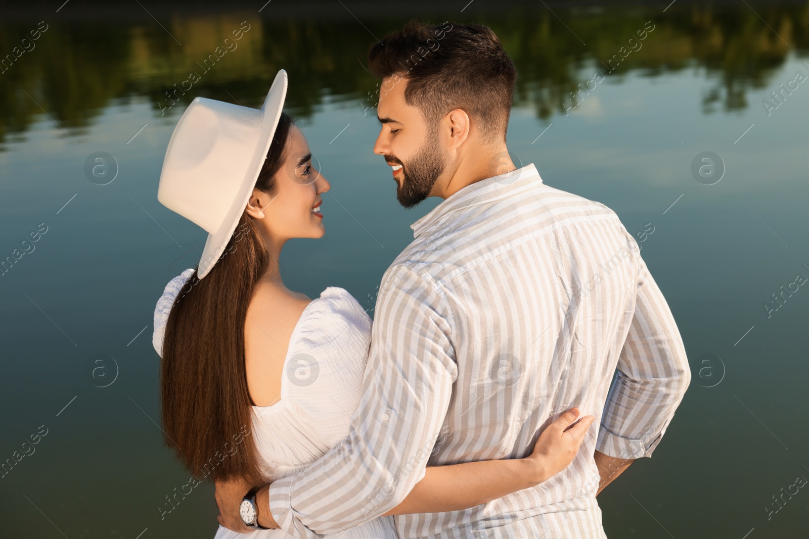 Photo of Romantic date. Beautiful couple spending time together near lake