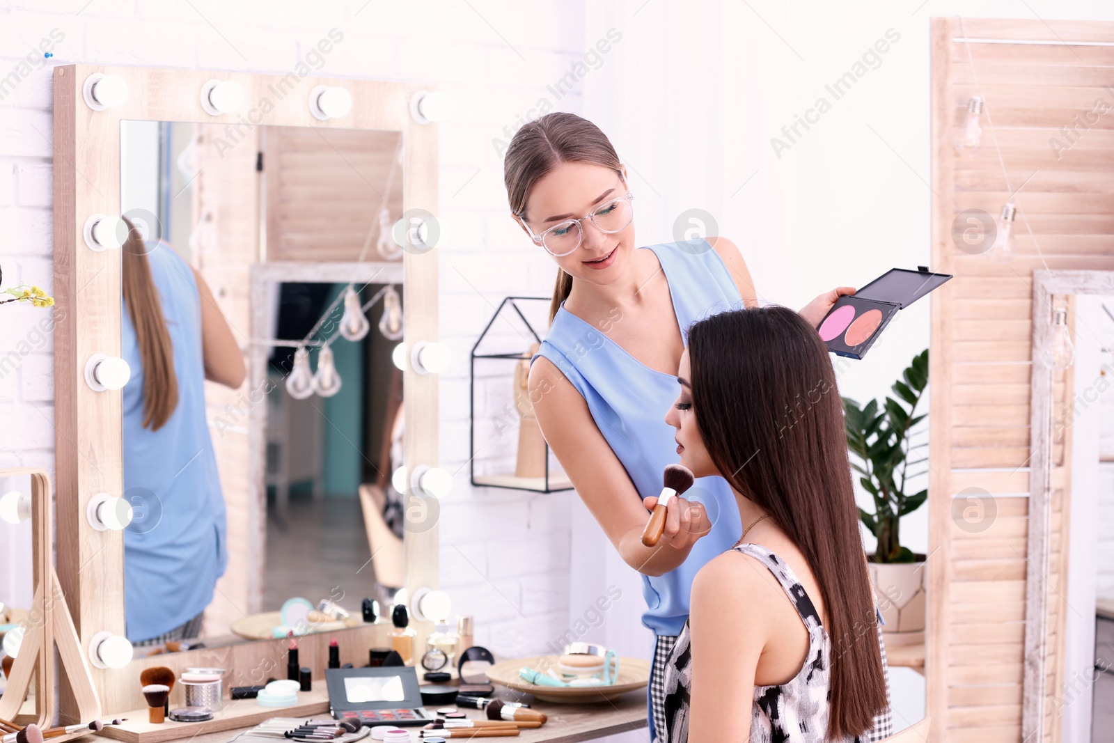 Photo of Professional visage artist applying makeup on woman's face in salon