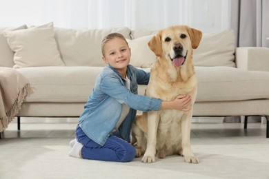 Photo of Cute child hugging her Labrador Retriever on floor at home. Adorable pet