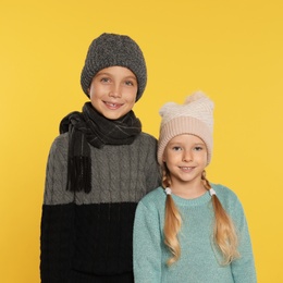 Photo of Cute little children in warm clothes on yellow background. Winter season