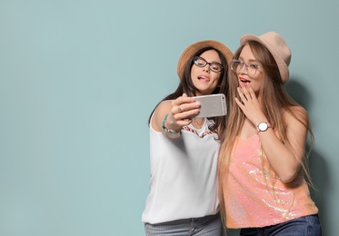 Attractive young women taking selfie on color background