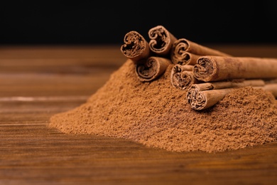 Photo of Aromatic cinnamon sticks and powder on wooden table, closeup