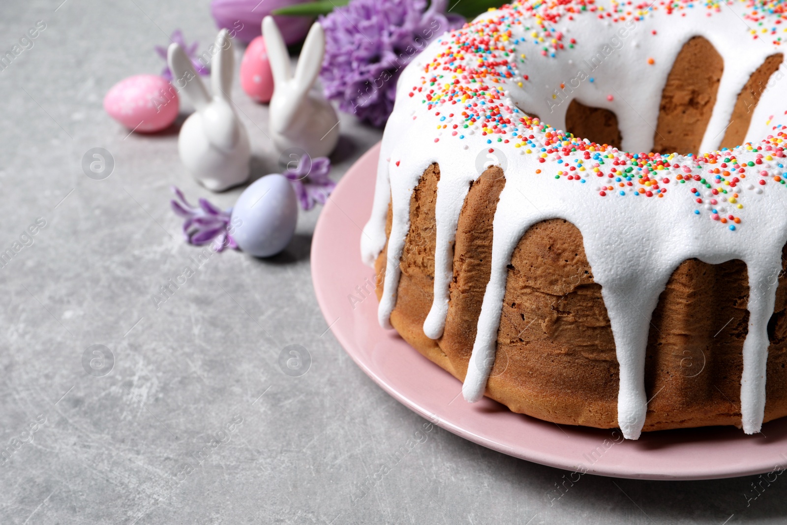 Photo of Glazed Easter cake with sprinkles on grey table, closeup. Space for text