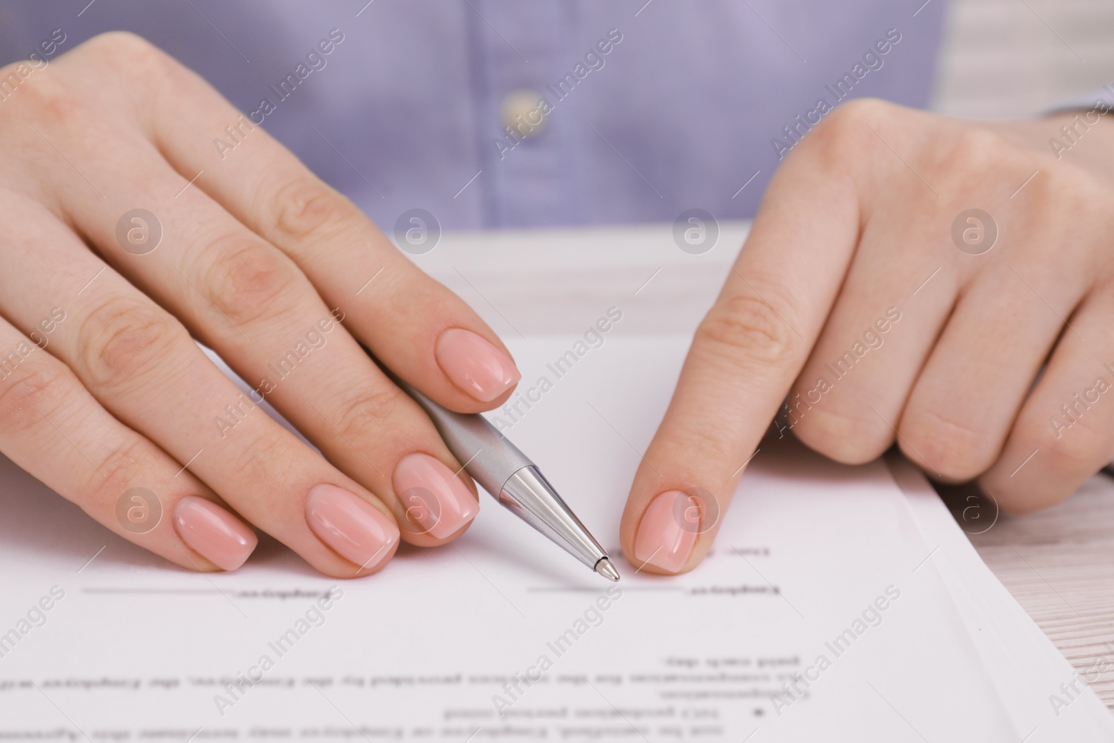 Photo of Woman signing document at table, closeup view