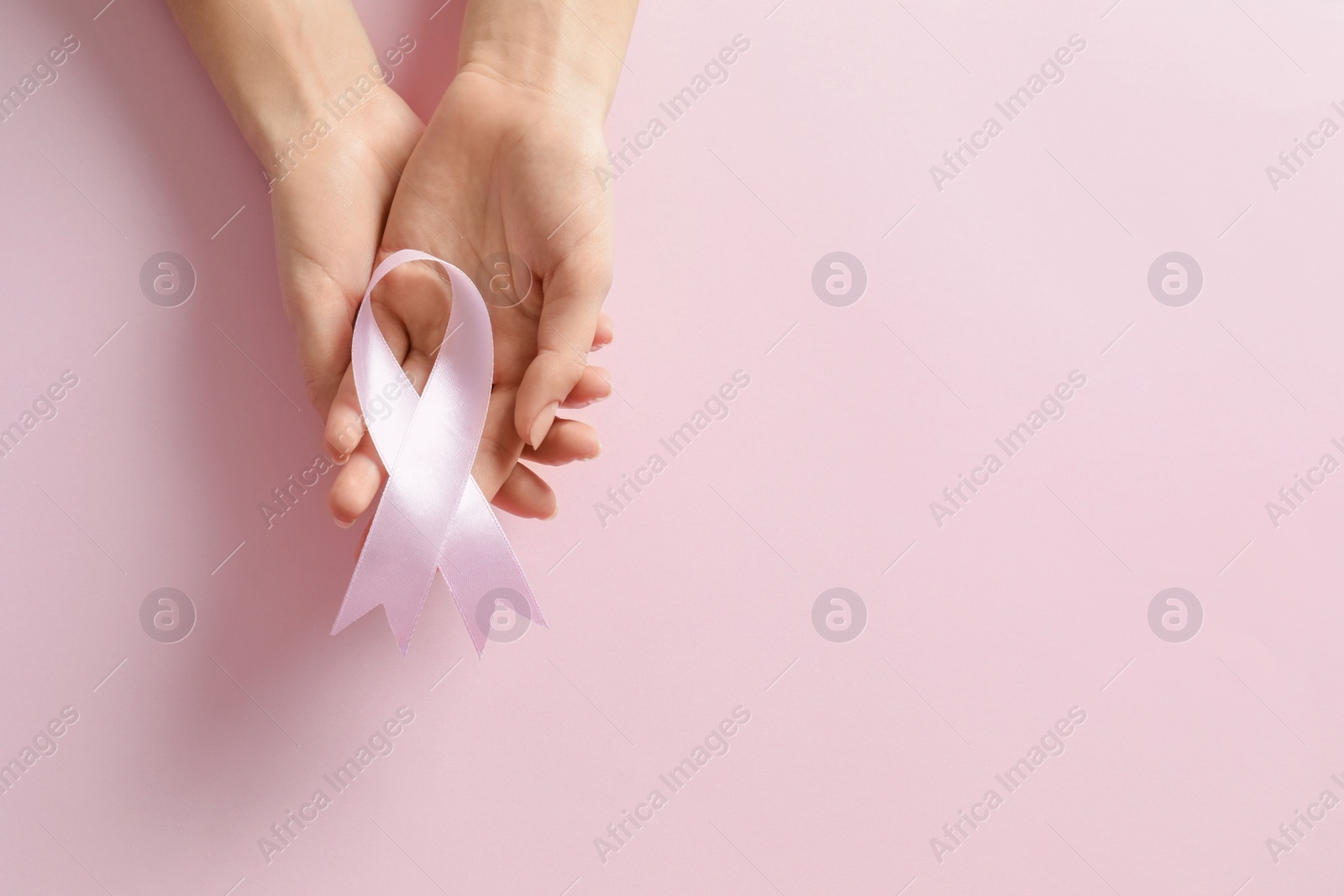 Photo of Woman holding pink ribbon on color background, top view with space for text. Breast cancer awareness