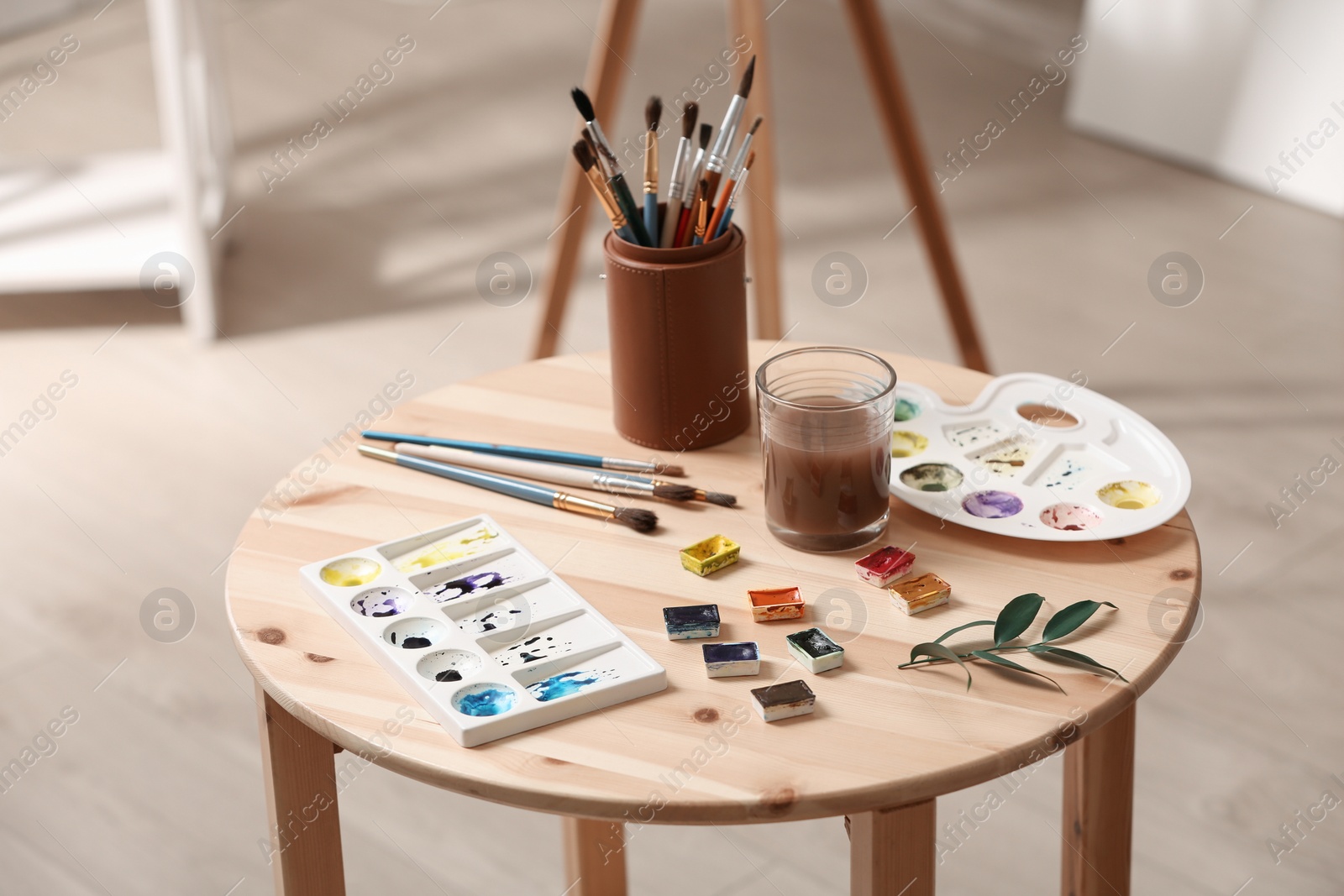 Photo of Composition with watercolor paints on wooden table in workshop