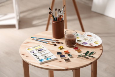 Photo of Composition with watercolor paints on wooden table in workshop