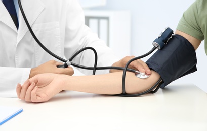 Doctor checking young woman's pulse in hospital