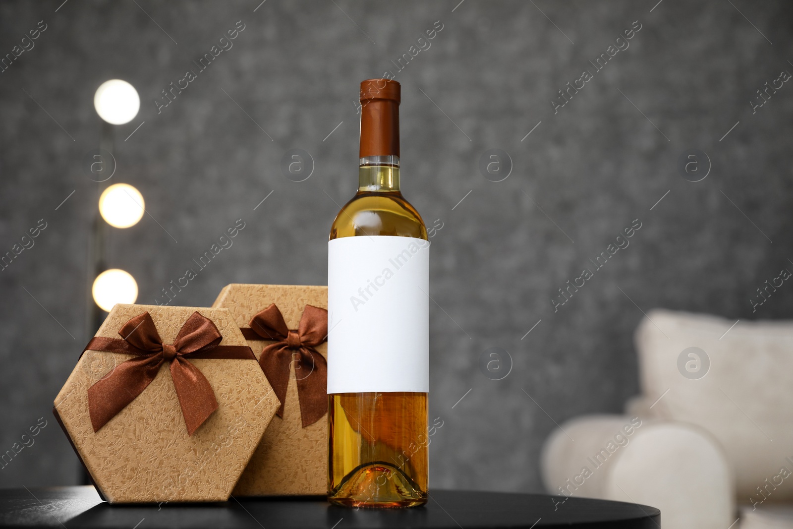 Photo of Gift boxes and bottle of wine on table in room. Space for design