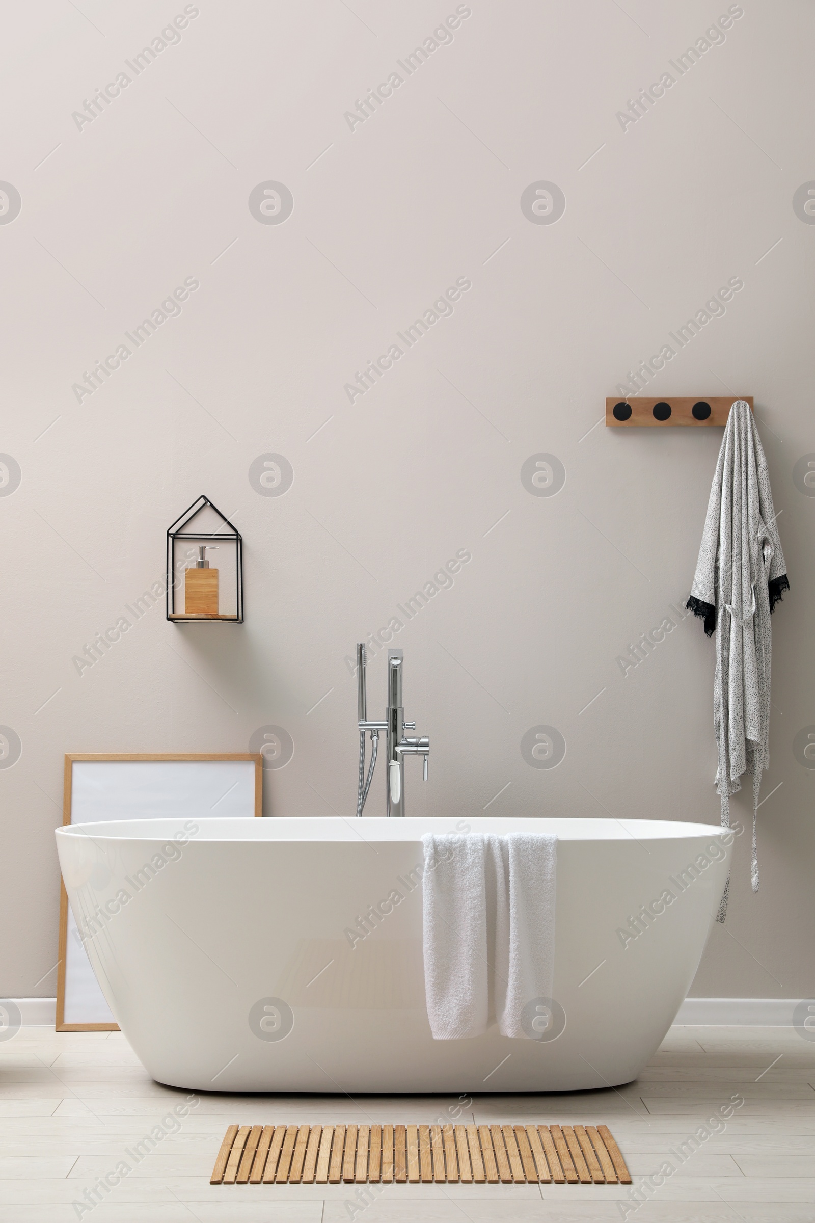 Photo of Modern ceramic bathtub near light wall indoors