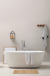 Photo of Modern ceramic bathtub near light wall indoors