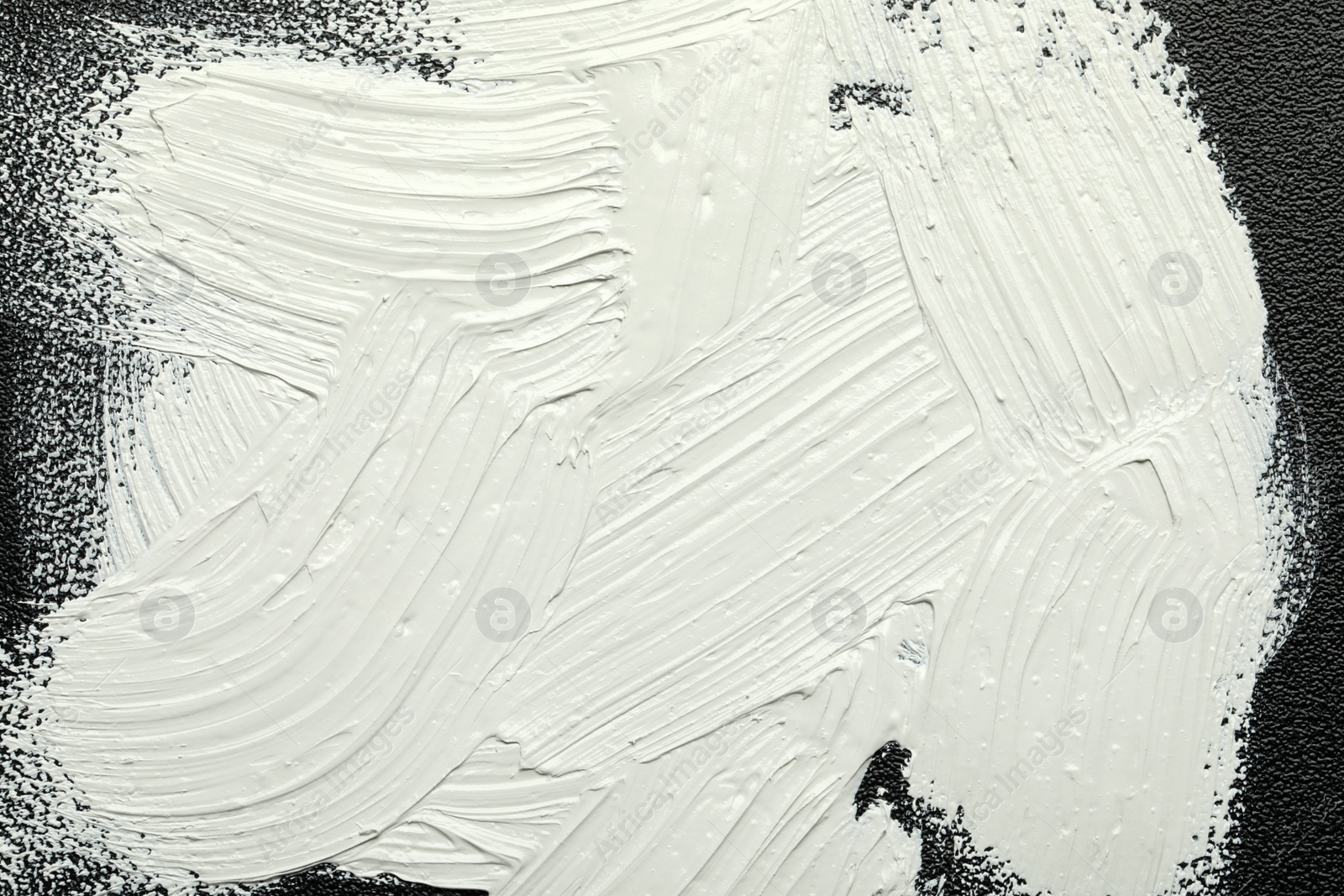 Photo of Strokes of white oil paint on black canvas, closeup