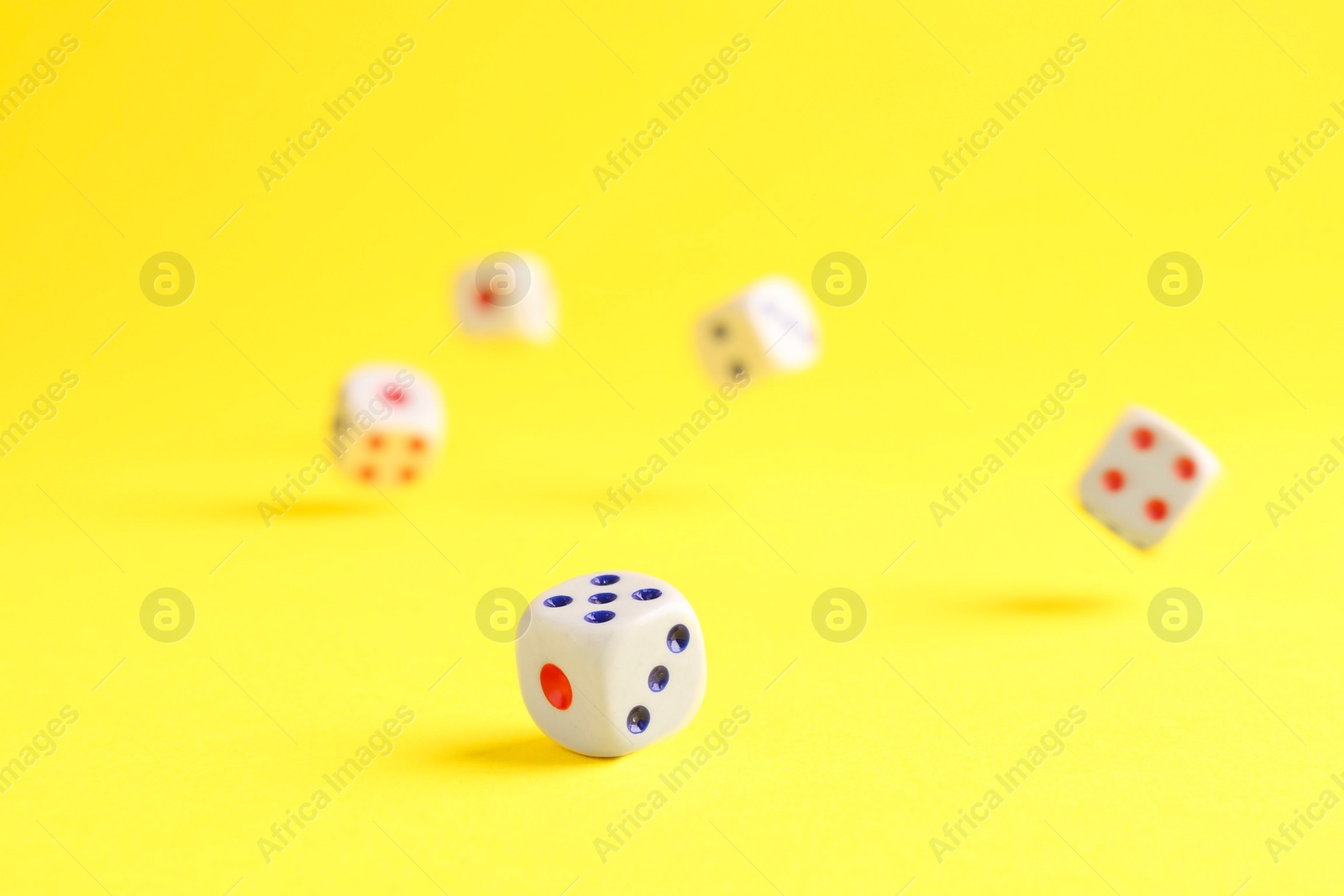 Photo of Many white game dices falling on yellow background