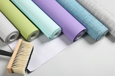 Photo of Different wallpaper rolls and brush on light background, above view