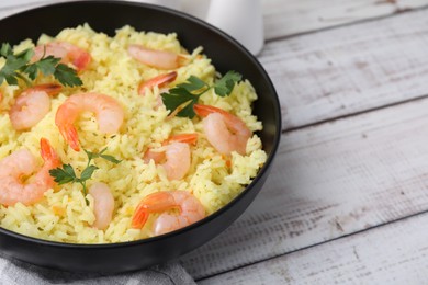 Photo of Delicious risotto with shrimps and parsley in bowl on white wooden table, closeup. Space for text