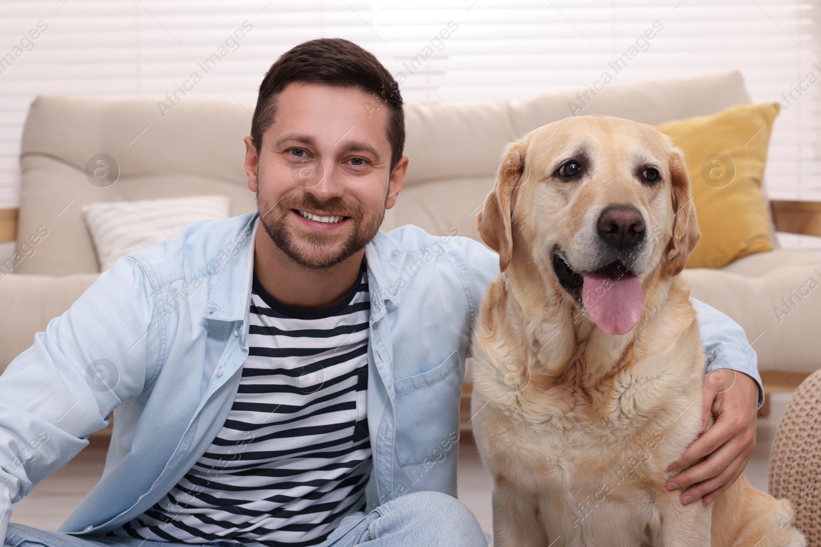 Photo of Man hugging with adorable Labrador Retriever dog at home. Lovely pet