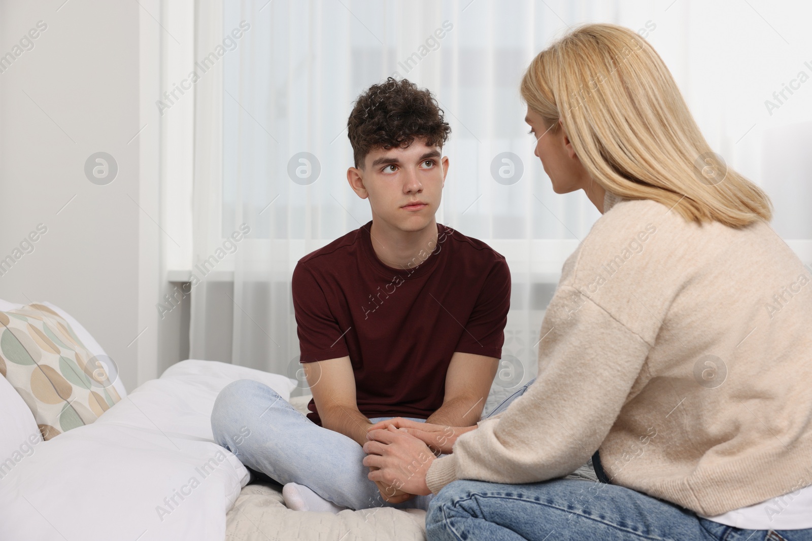 Photo of Mother consoling her upset son in bedroom, space for text. Teenager problems