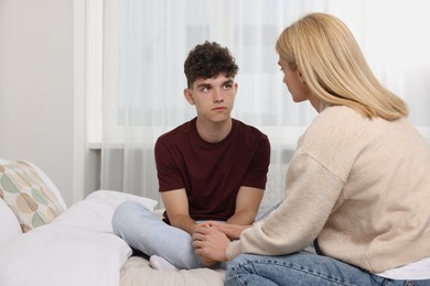 Photo of Mother consoling her upset son in bedroom, space for text. Teenager problems