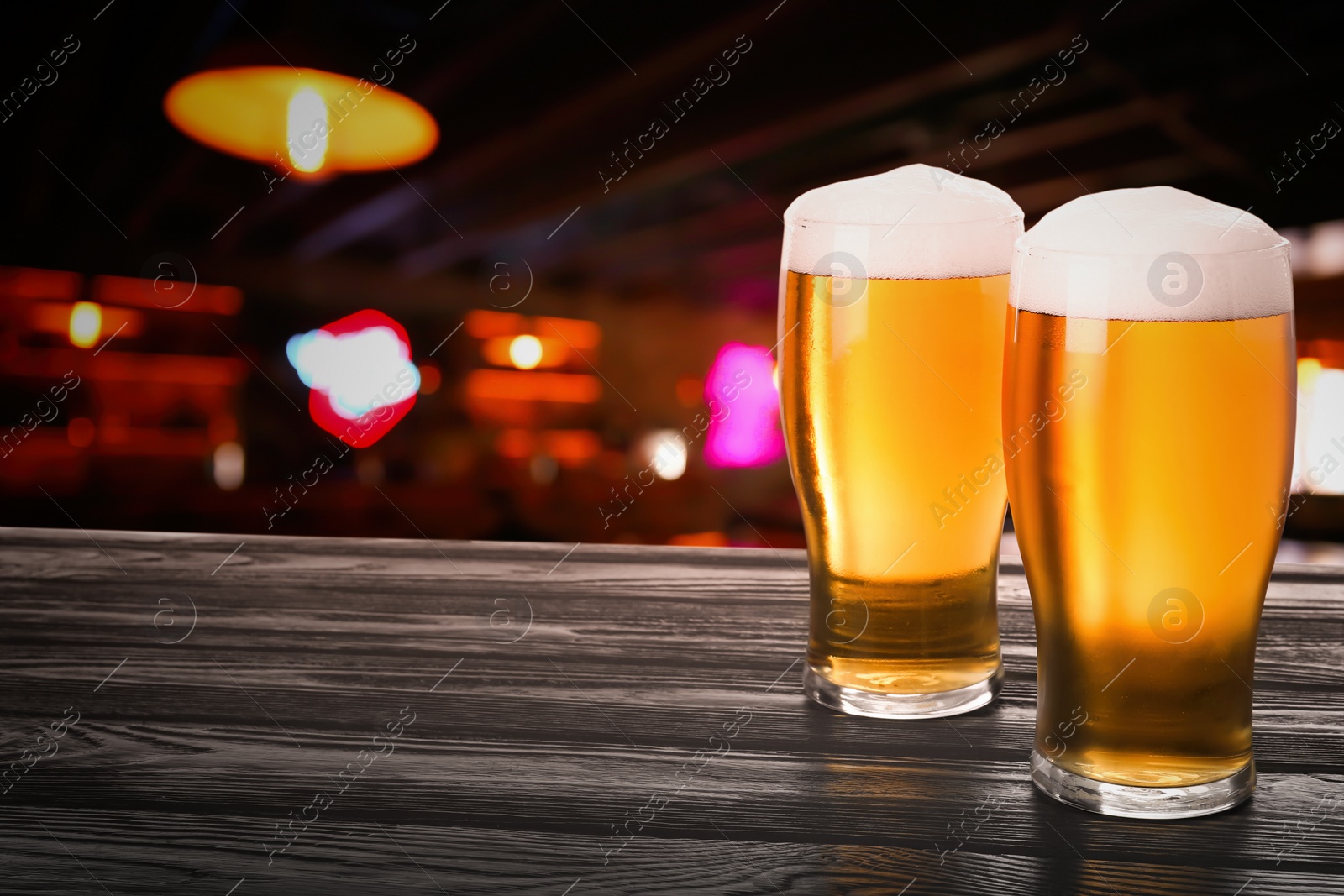 Image of Fresh cold beer on wooden table in pub, space for text