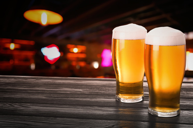 Fresh cold beer on wooden table in pub, space for text