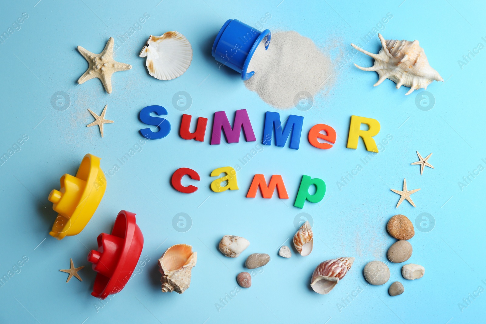 Photo of Flat lay composition with phrase SUMMER CAMP made of magnet letters on light blue background