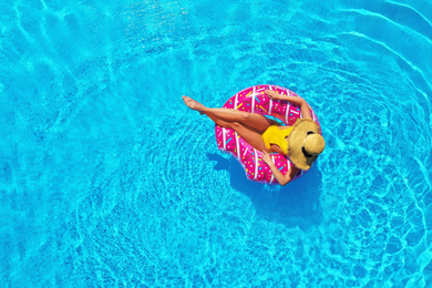 Young woman with inflatable ring in swimming pool, top view