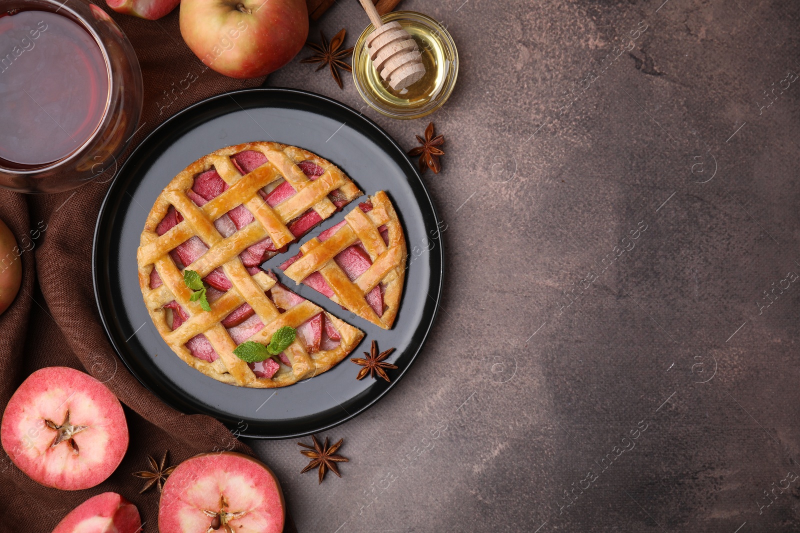 Photo of Delicious apple pie with mint and ingredients on brown table, flat lay. Space for text