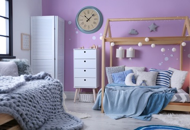 Photo of Child's room interior with comfortable bed and garland