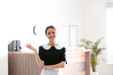 Portrait of young chambermaid near reception in hotel