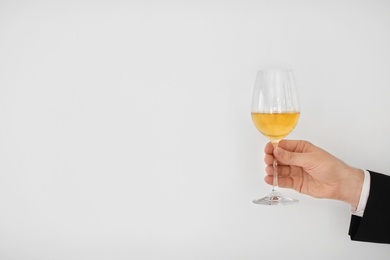 Photo of Man holding glass of wine on light background