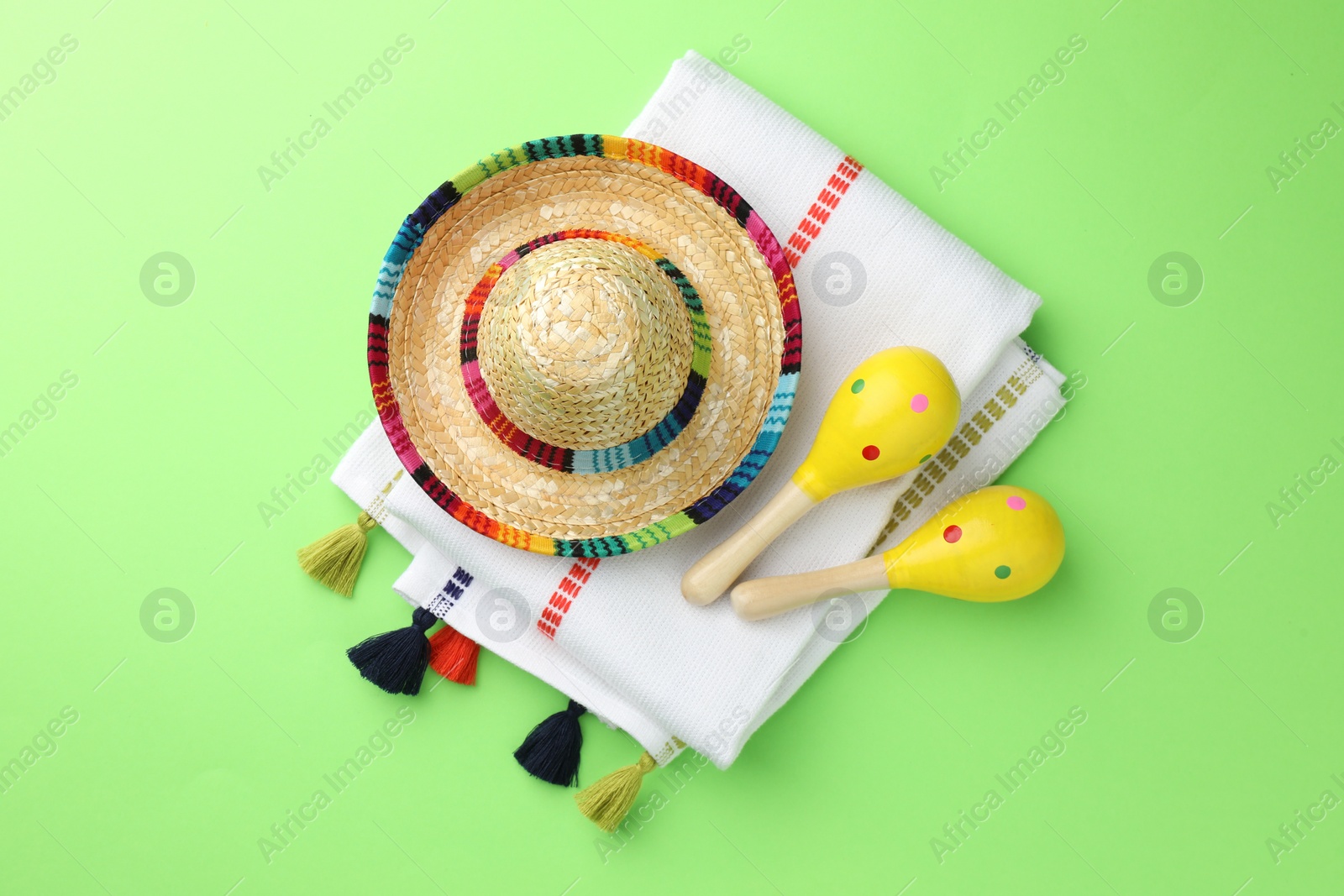 Photo of Mexican sombrero hat, maracas and poncho on green background, flat lay