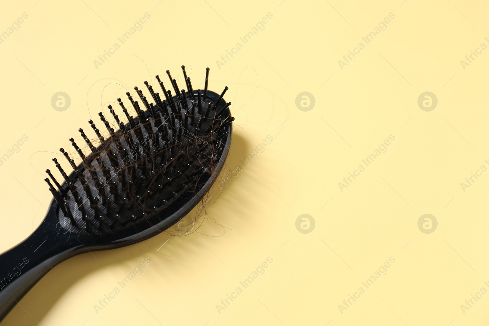 Photo of Brush with lost hair on yellow background, space for text