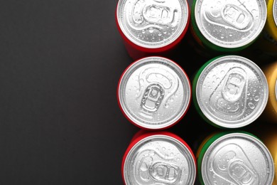 Photo of Energy drinks in wet cans on dark background, top view. Space for text