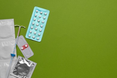 Photo of Contraception choice. Pills, condoms and intrauterine device on green background, flat lay. Space for text