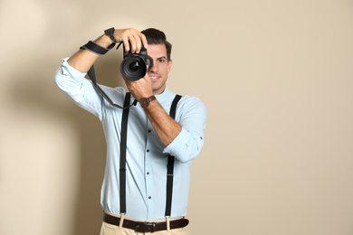 Photo of Professional photographer working on beige background in studio. Space for text