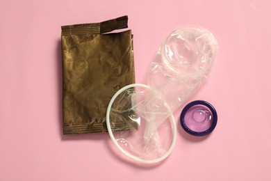 Photo of Unpacked female, male condoms and torn package on light pink background, flat lay. Safe sex