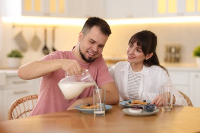 Happy couple having tasty breakfast at home