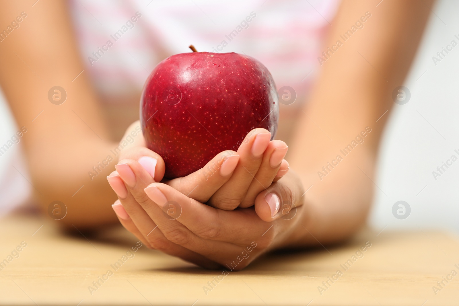 Photo of Woman holding fresh red apple at table, closeup