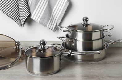 Photo of New cookware set on wooden countertop near light wall