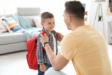 Young man helping his little child get ready for school at home