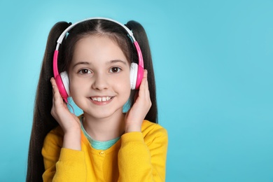 Photo of Cute girl enjoying music in headphones on color background. Space for text