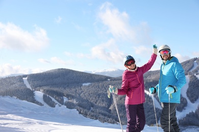 Photo of Happy couple with ski equipment spending winter vacation in mountains. Space for text